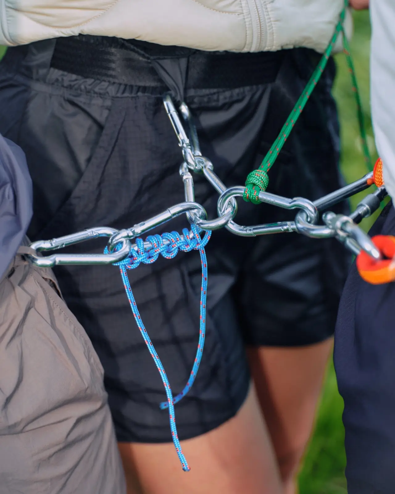 Close-up of metal carabiners and color-coded cords attached to hiking gear