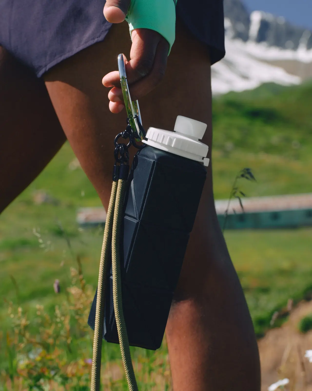 Hiker holding a carabiner attached to a black rectangular water flask